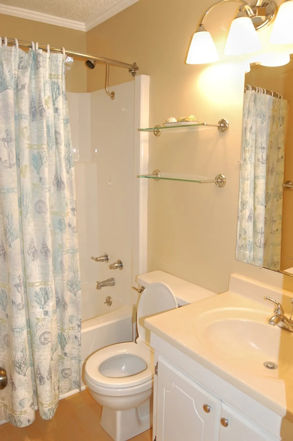 A fresh, inviting bathroom scene featuring a shower with a patterned curtain, sink, and toilet. The space is clean, functional, and bright, hinting at the accessible amenities available within the resort.
